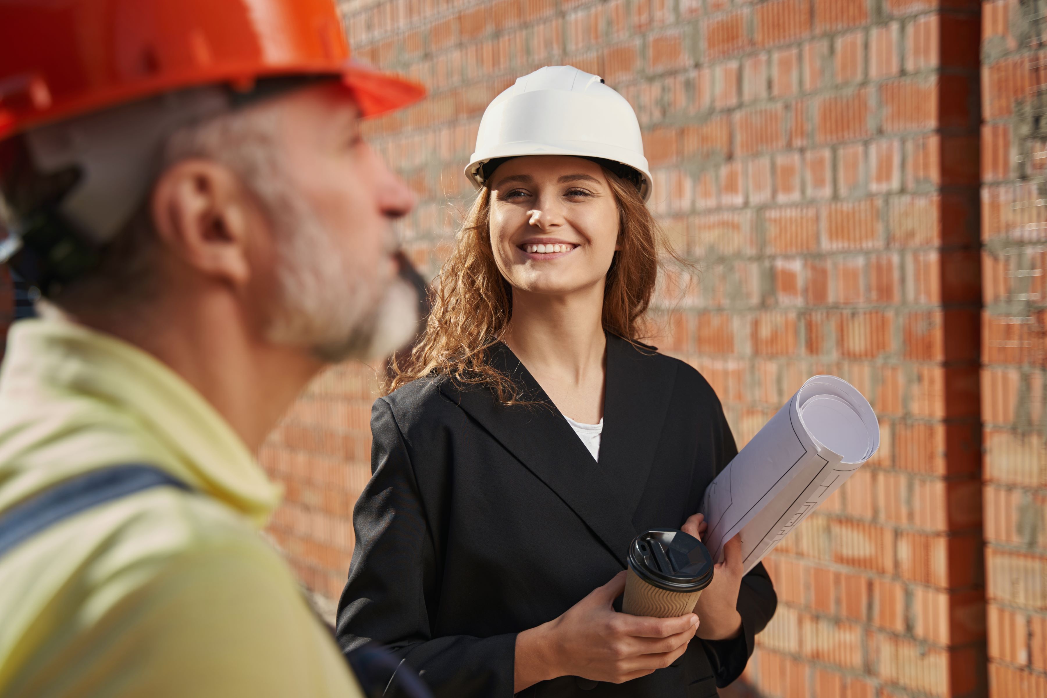 Female construction worker holding plans and coffee cup